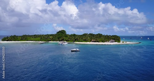 Fiji Tavarua island surrounded by fishing and tour boats in the aquamarine water, aerial drone parallax establishing shot photo