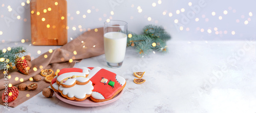 Plate with tasty Christmas cookies and glass of milk on table