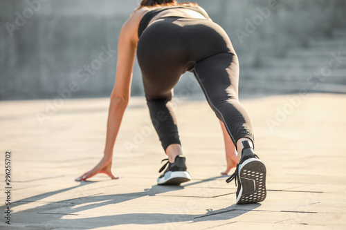 Sporty young woman in crouch start position outdoors