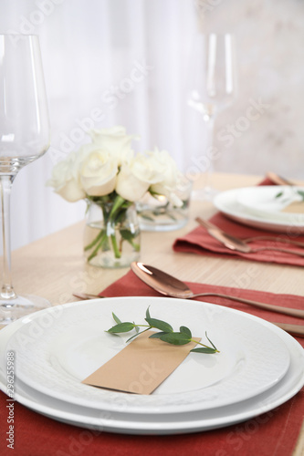 Elegant festive table setting with blank card in restaurant