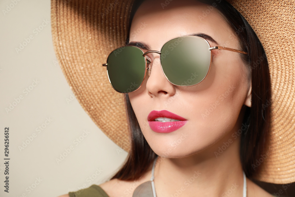 Beautiful woman in stylish sunglasses and hat on beige background Beautiful woman in stylish sunglasses and hat on beige background