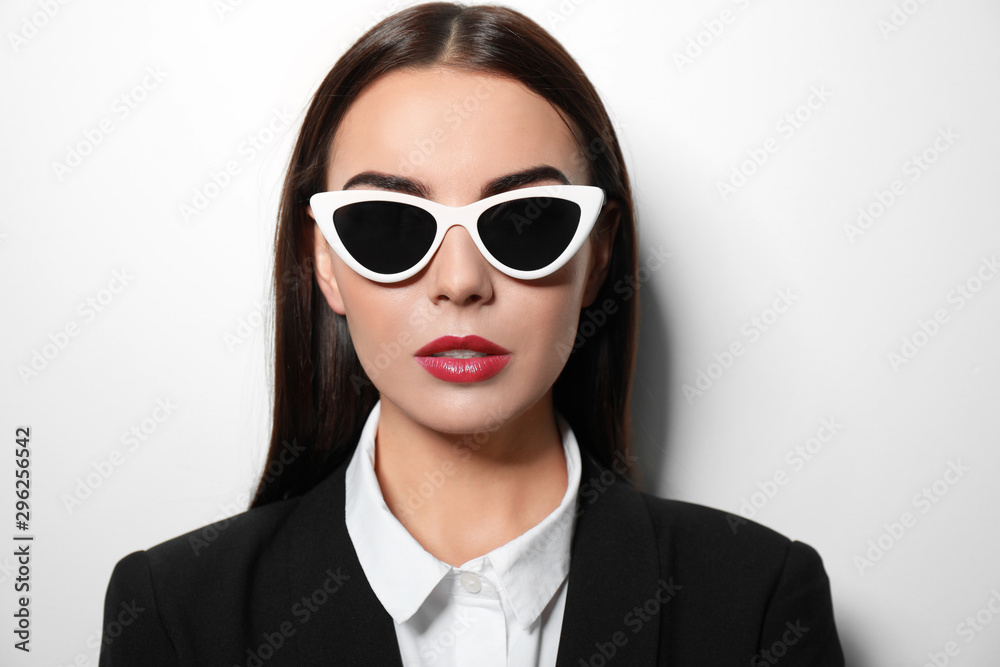 Young businesswoman in stylish sunglasses on light background Young businesswoman in stylish sunglasses on light background