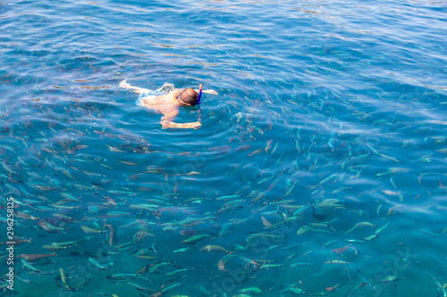 A man swims in the blue water of the sea