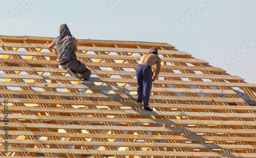 Workers are building the roof of the house from wood