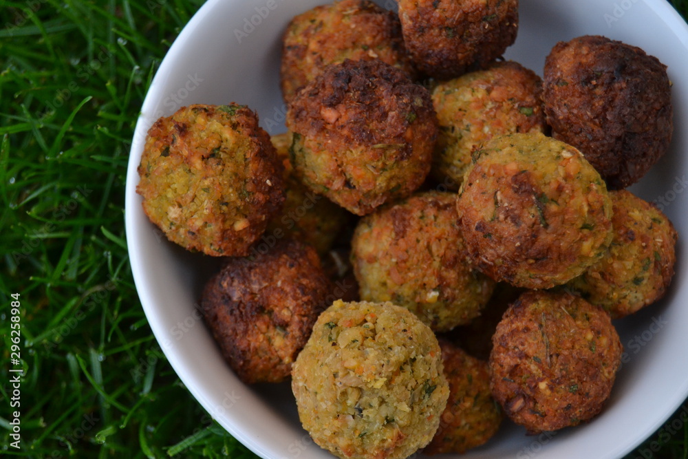 falafels in the white bowl on the green grass. fresh tasty homemade falafel balls. chickpeas balls with seasoning. falafels in the white bowl on the green grass. fresh tasty homemade falafel balls. chickpeas balls with seasoning.