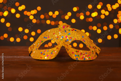 Festive mask on wooden background against blurred lights