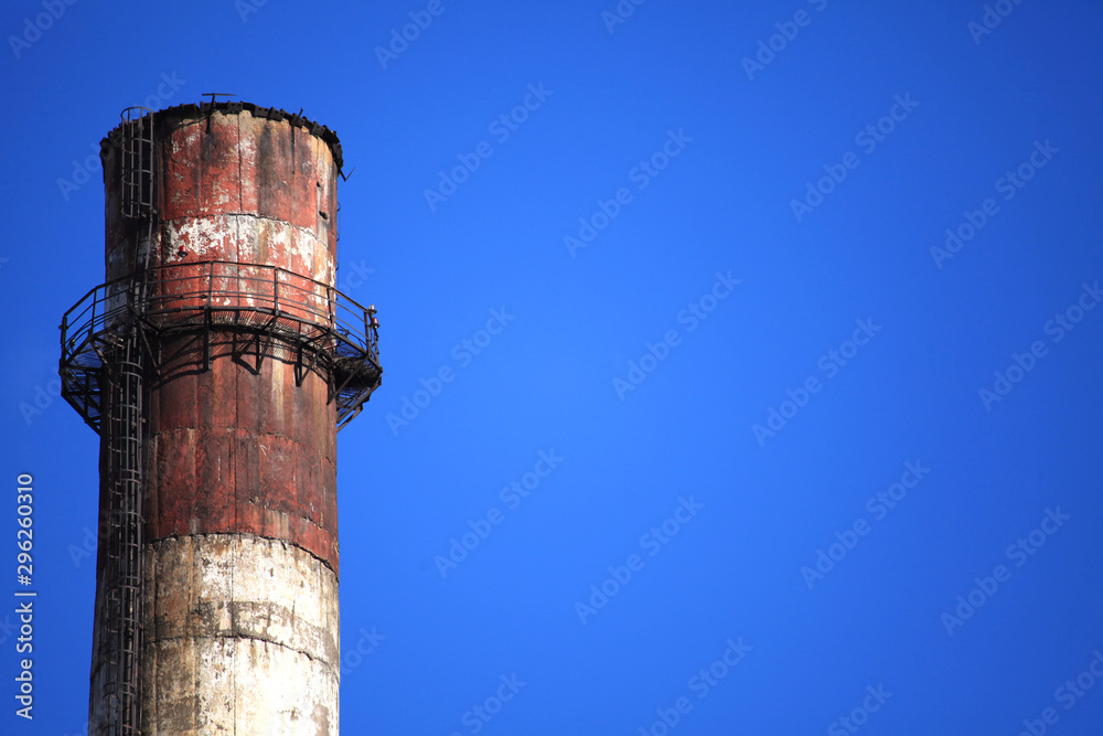 Single chimney top on the winter sky background. Heating season. The view of plant chimney, constructed with prefabricated concrete blocks. Thermal electric station, combined heat and power plant