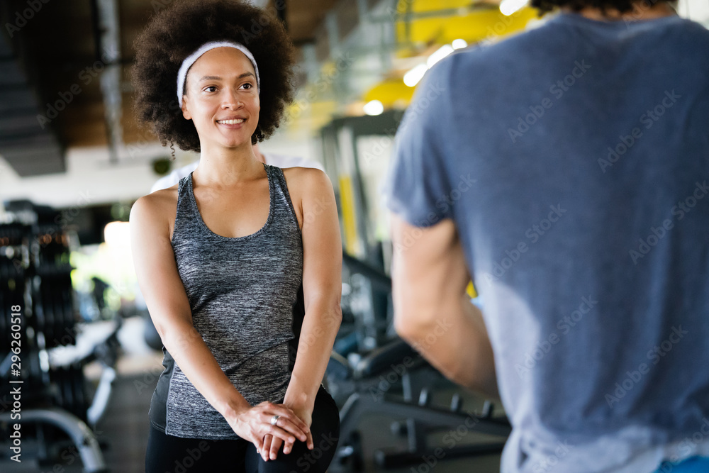 Young fit man doing exercises with personal trainer in gym Young fit man doing exercises with personal trainer in gym