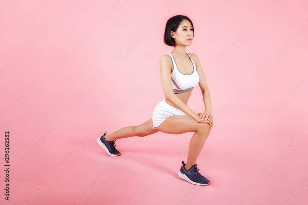 Healthy lifestyle. Beautiful asian woman stretching legs muscles isolated on pink background.