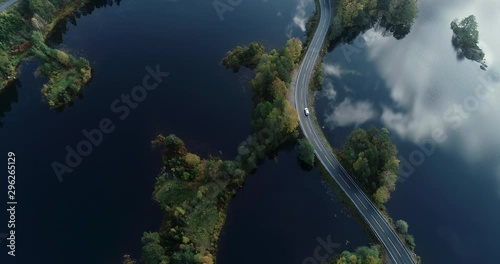 Aerial view of a road between islands. White car drives on the road.
