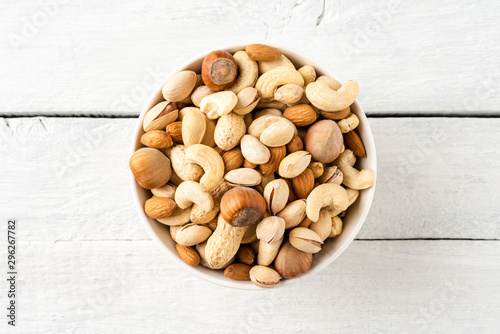 Mixed dried nuts (almonds, pistachios, peanuts, hazelnuts and cashews) in bowl on wooden table. Top view