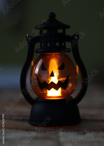 Close-up lantern jack. Lamp in form terrifying smiling on side the glass. Typical decoration for Halloween night party. Orange light is basic stone of this national holiday
