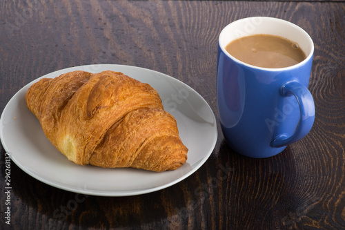 croissant on a white plate and coffee in a purple mug