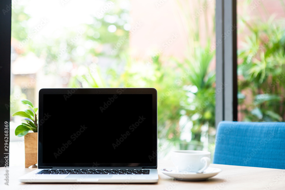 Mockup of laptop computer with empty screen with coffee cup on table of the coffee shop background Mockup of laptop computer with empty screen with coffee cup on table of the coffee shop background