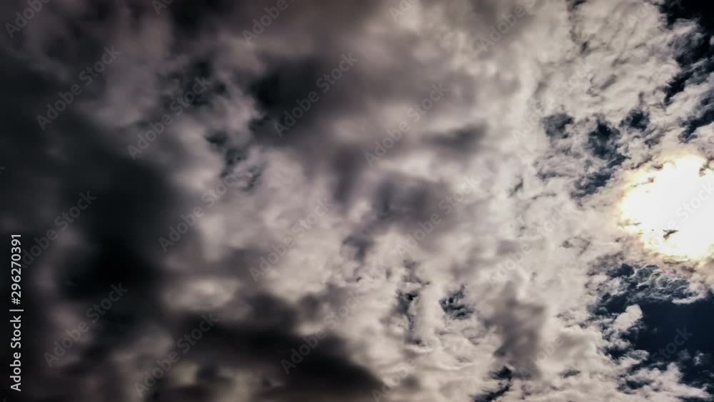 4K Timelapse of the white puffy clouds moving very fast over the clear blue sky with the Sun rising in the background. 4K Timelapse of the white puffy clouds moving very fast over the clear blue sky with the Sun rising in the background.