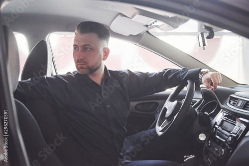 Going back. Side view of man sitting in the modern car with black interior photo