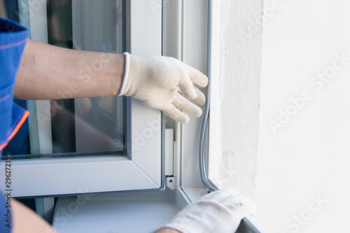 Φωτογραφία the hand of the master in a protective glove, inserts into the frame of the plas