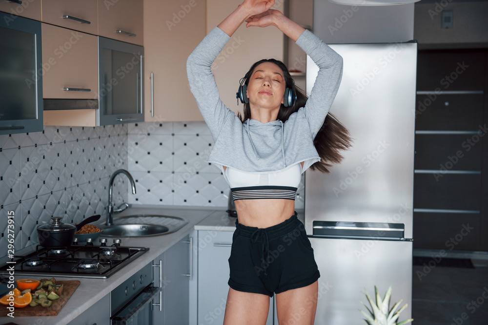 Dancing to the music. Girl in the modern kitchen at home at her weekend in the morning time Dancing to the music. Girl in the modern kitchen at home at her weekend in the morning time