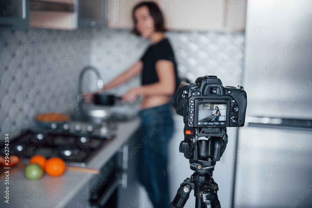 Professional camera on tripod. Girl in the modern kitchen at home at her weekend time in the morning Professional camera on tripod. Girl in the modern kitchen at home at her weekend time in the morning