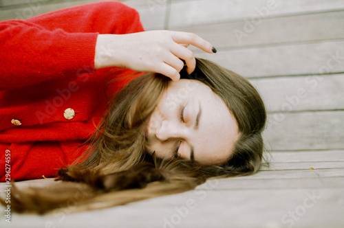 brunette in a red jacket lies on a wooden background photo