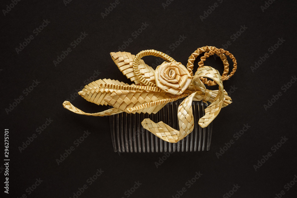 Fototapeta premium Ornamental hair comb with straw flowers on a dark background