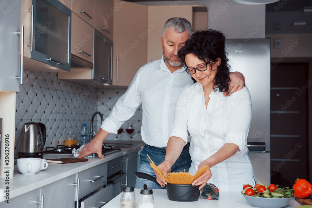 That's my secret recipe. Man and his wife in white shirt preparing food on the kitchen using vegetables That's my secret recipe. Man and his wife in white shirt preparing food on the kitchen using vegetables
