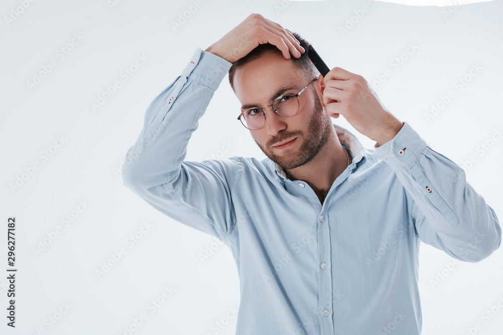 Getting prepared for the business meeting. Man in official clothes stands against white background in the studio Getting prepared for the business meeting. Man in official clothes stands against white background in the studio