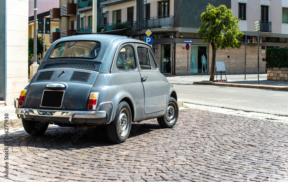 Vintage small car on traditional italian paved street.