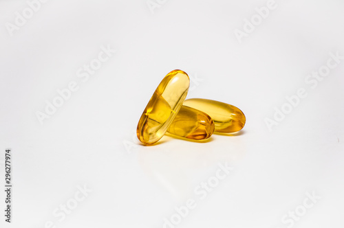 close up of three capsules filled with omega 3 fish oil fatty acids lay in a heap on a light gray background, concept of health care and cardiovascular system