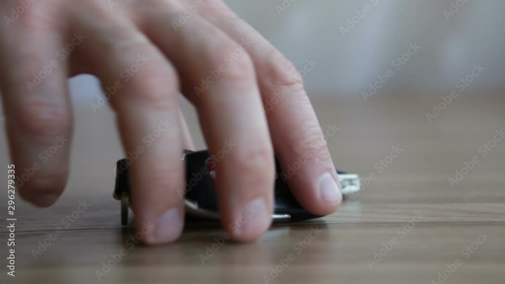 A man picks up car keys from the table. Car keys are on the table. A man picks up car keys from the table. Car keys are on the table.
