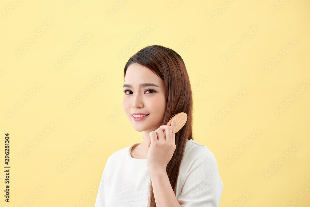 Portrait of beautiful young woman combing her hair and smiling Portrait of beautiful young woman combing her hair and smiling