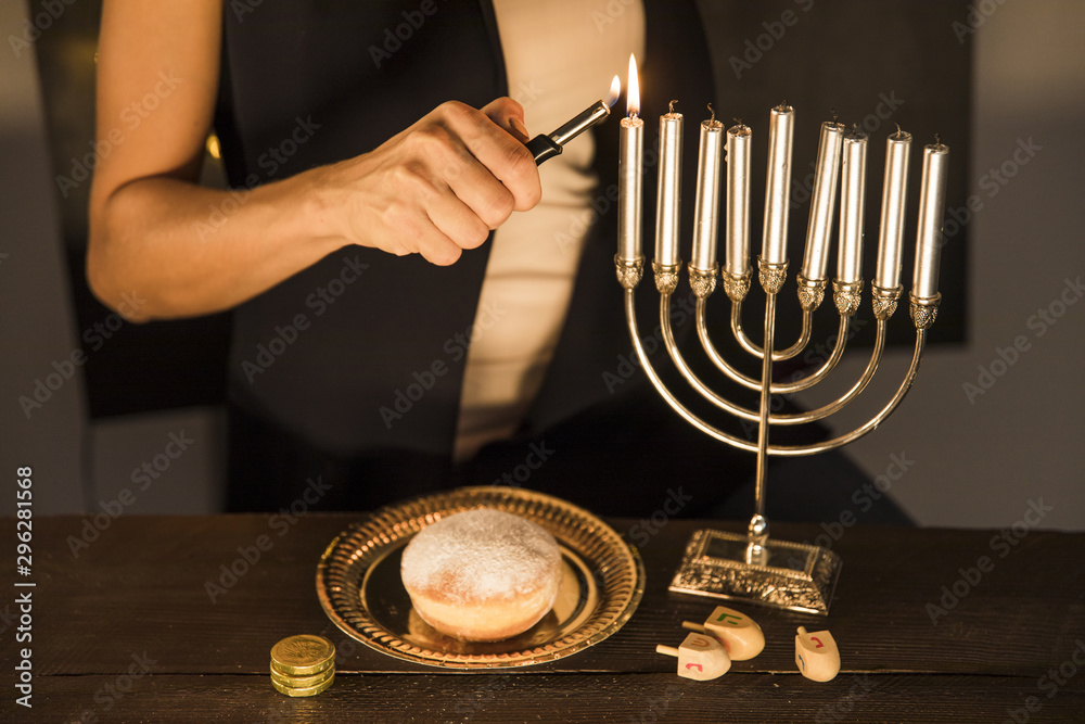 Crop woman lighting candles on menorah - obrazy, fototapety, plakaty 