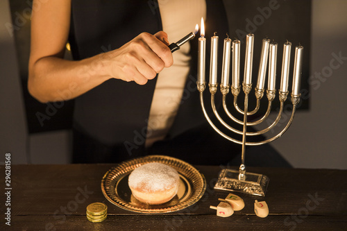 Fotografie Crop woman lighting candles on menorah
