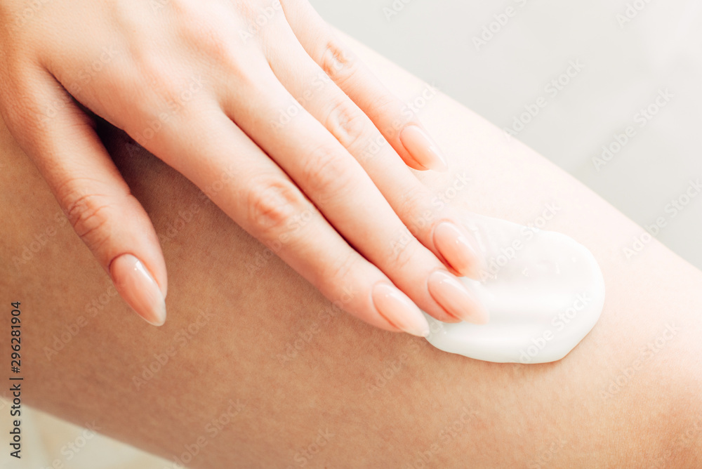 Fototapeta premium Close-up of a woman applying anti-aging cream on her leg