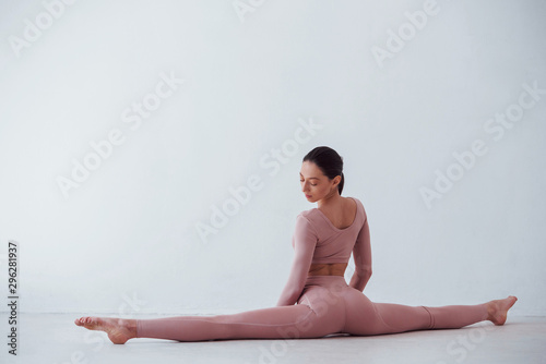 Doing the splits. Caucasian pretty woman doing exercises against white background in the studio