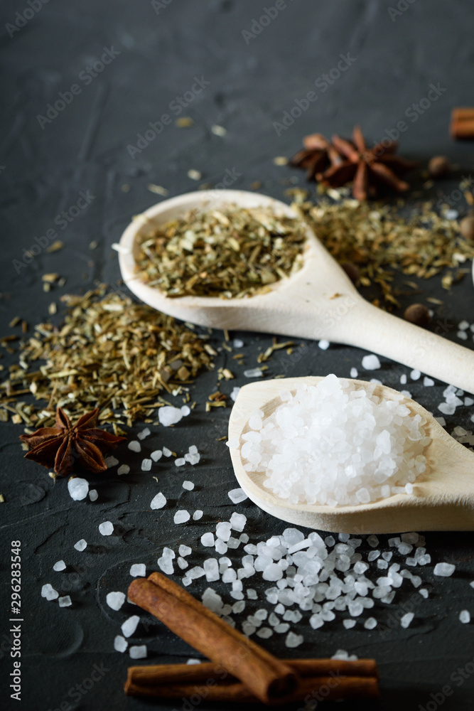 Fototapeta premium Wooden spoon with Italian seasoning-dried oregano with thyme,vegetables.Oregano in a wooden spoon on a rocky concrete dark black background with a place for text Top view