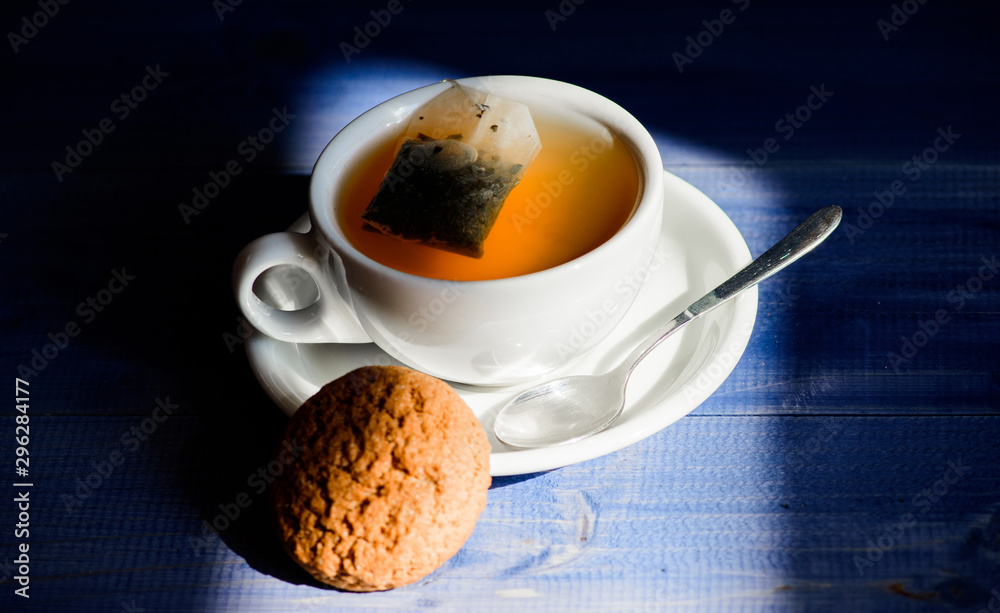 Quick snack concept. Relaxing chamomile tea. Cup mug hot tea and oat  cookie. Mug filled tea close up. Herbal green or black whole leaf. Process  tea brewing ceramic mug. Inspiration and peaceful