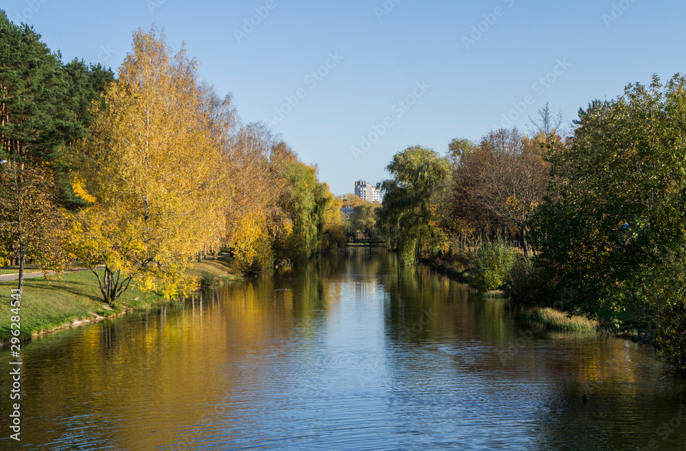 Autumn park with yellow leaves and trees with a river and reflection in the water and blue sky. Autumn park with yellow leaves and trees with a river and reflection in the water and blue sky.