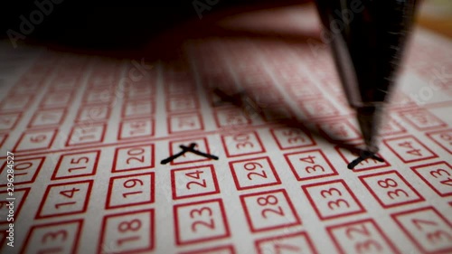 hand fill out lottery ticket. cross out lucky numbers on play slip