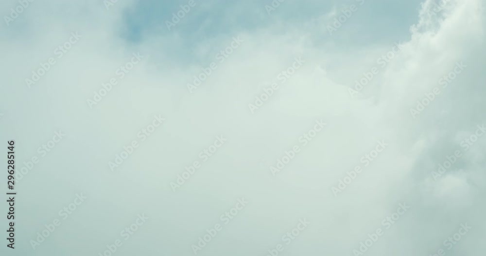 Aerial view flying through clouds in a blue sky, view from the front of an airplane flying through the clouds