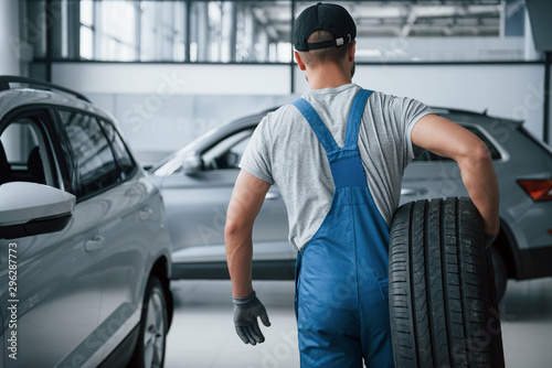 This needs to be taken away. Mechanic holding a tire at the repair garage. Replacement of winter and summer tires