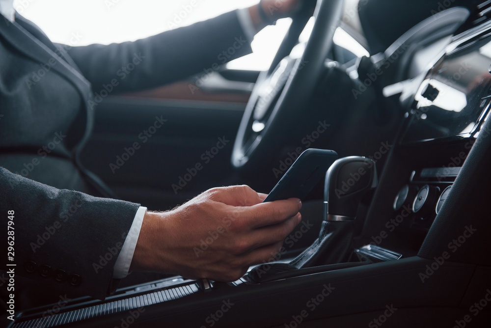 Don't use phone and drive. Modern businessman trying his new car in the automobile salon