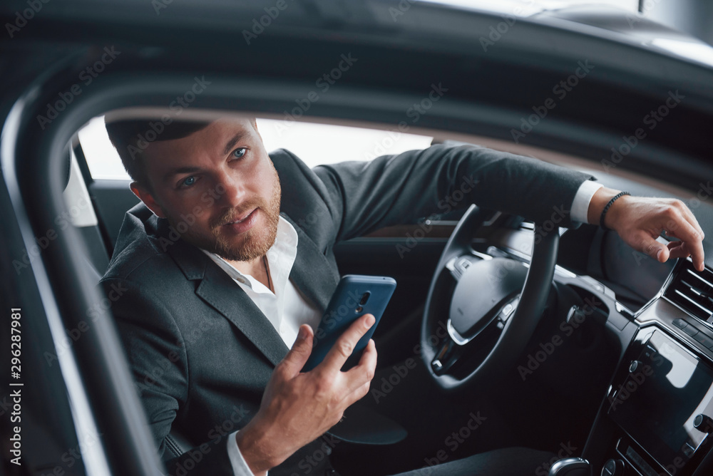 Looking through the window. Modern businessman trying his new car in the automobile salon