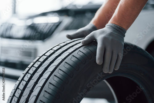 Hands only. Mechanic holding a tire at the repair garage. Replacement of winter and summer tires