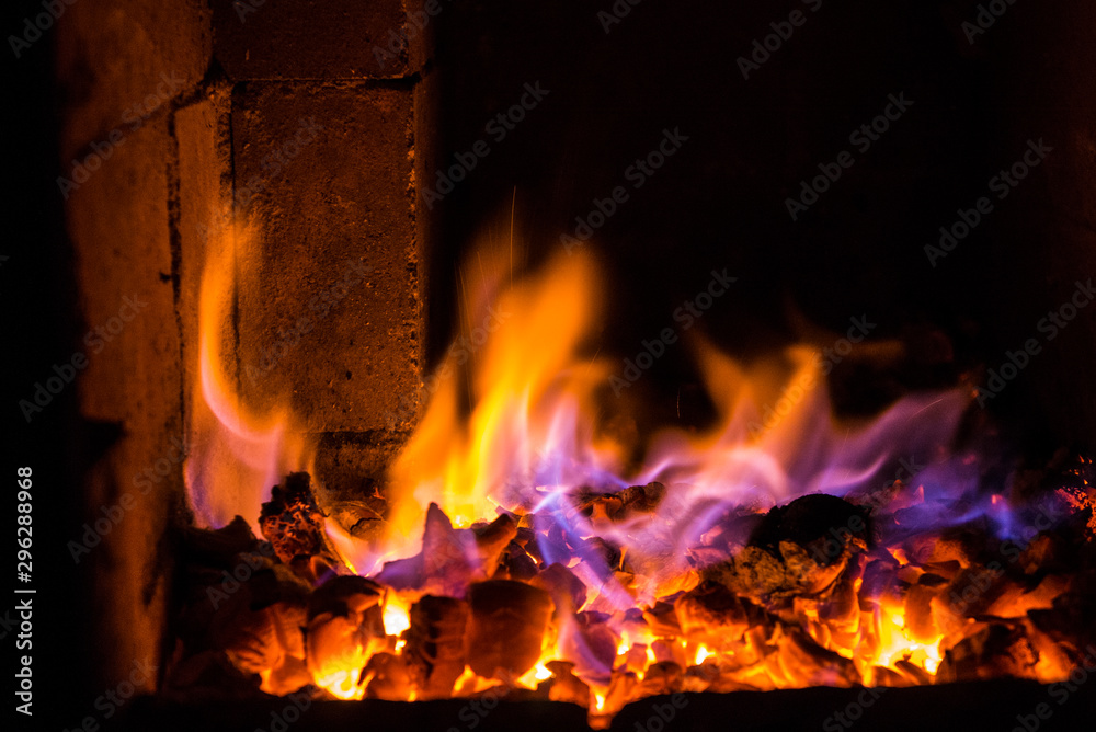 Bright fire burns on coals close-up. Carbon dioxide flies out with a blue spark.