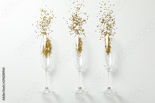 Champagne glasses with glitter on white background, space for text