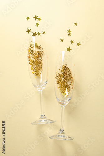 Champagne glasses with glitter on beige background, space for text