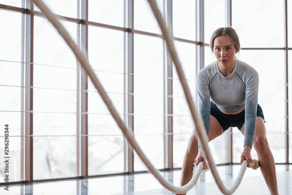 Pretty girl doing crossfit. Sportive young woman have fitness day in the gym at morning time