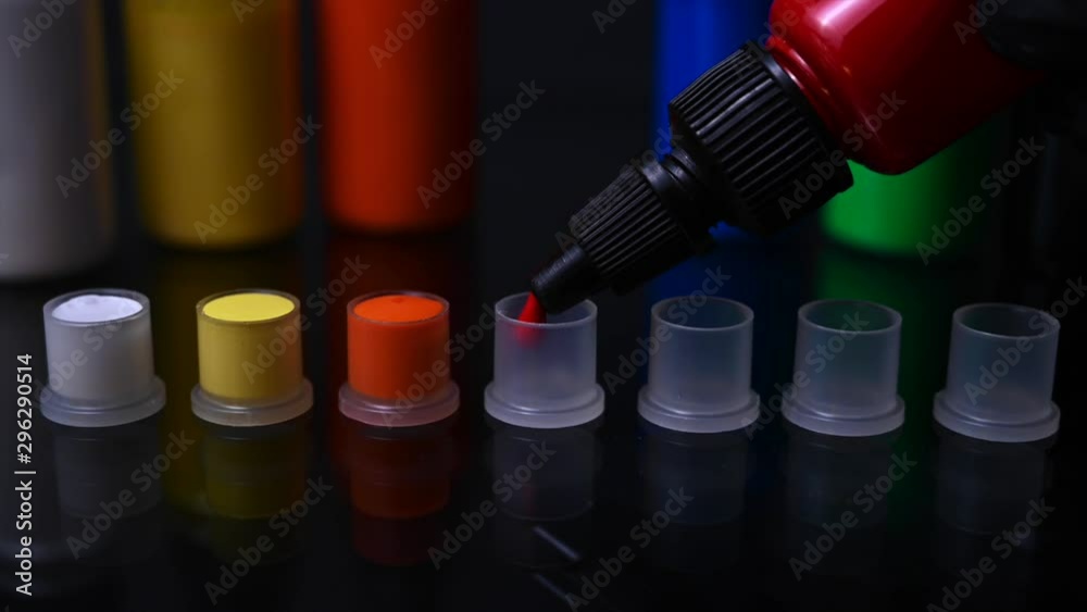 Closeup of tattoo artist pouring red ink in cap