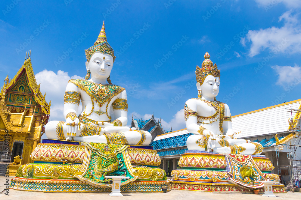 White and golden Buddha Statue with the church in blue sky background at Wat Charoen Rat Bamrung (Wat Nong Pong Nok) in Nakhon Pathom Province, Thailand White and golden Buddha Statue with the church in blue sky background at Wat Charoen Rat Bamrung (Wat Nong Pong Nok) in Nakhon Pathom Province, Thailand